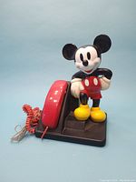 Front view of the vintage Mickey Mouse telephone with handset and coiled cord on black base