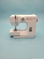 Front view of white Singer M1000 compact sewing machine showing stitch dial and needle area.