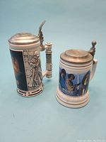 Two Star Wars tankards shown together; taller tankard with sculpted figure handle and colorful scenes, shorter tankard with character scene on white body.