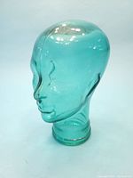 Side profile view of the turquoise glass mannequin head showing facial features in the translucent glass.