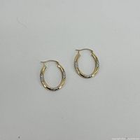 Pair of yellow and white gold hoop earrings on flat white background