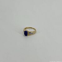Front angle showing the blue cabochon stone and side inset stones on gold band