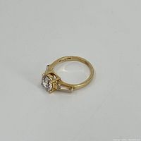 Front view of 14k gold ring with cubic zirconia center stone and baguette side stones showing inside 14k and CZ markings.