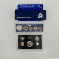 Top view photo of two United States coin proof sets from 1967 and 1970 showing coins and outer boxes.