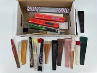 Box containing 16+ assorted hand fans in various colors and designs, some in packaging