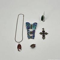 Group view of six sterling silver jewelry items including necklace, ring, pins, pendant, and hair clip on white background.