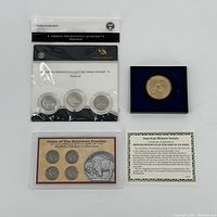 Photo of America the Beautiful quarters three-coin set in original packaging, George Washington $1 coin in display case, Buffalo Nickel collection with certificate.
