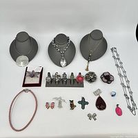 Full display of costume jewelry including necklaces on busts, rings on stand, brooches, pendants, and earrings