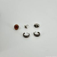 Five pieces of sterling silver jewelry including three rings and one pair of half hoop earrings with marcasite detail.