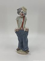 Front view of the porcelain clown figure showing details of face, hat, shirt, pants, and lambs in pockets.