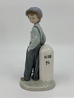 View of the boy leaning against the stone marker from the back side