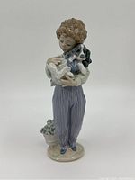 Front view of the Lladro porcelain figurine showing the boy holding his dog and the flowerpot at his feet.