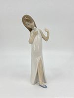 Front and side view showing the girl singing, holding a microphone, wearing a white dress with slit and blue shoes.