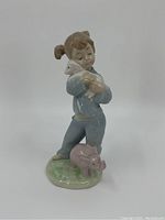 Front view of porcelain figurine showing boy holding lamb and elephant at his feet.