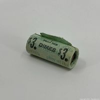 Single roll of Harrah's $3 dime coins wrapped in green paper with partial text visible.
