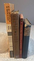Four vintage books standing upright showing front covers and spine details.