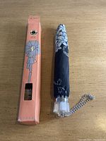 Umbrella folded and placed next to original pink Embrella box on wooden surface.