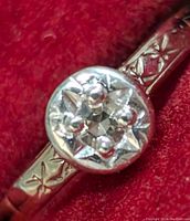 Close-up photo of gold ring displaying detailed star pattern on band and diamond centerpiece.