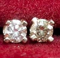 Close-up photo showing two round-cut lab-grown diamonds mounted in 14K yellow gold prong settings.