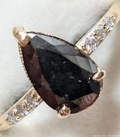 Top view of pear-shaped black diamond and white diamond shoulder accents