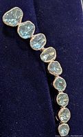 Close-up front view of the curved brooch showing the ten irregular-shaped blue diamonds set in sterling silver.
