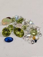 Close-up of various loose gemstones in mixed cuts and colors on white background