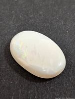 Top view of oval white Australian opal cabochon showing subtle iridescence and overall smooth surface.