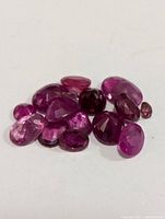 Loose faceted ruby gemstones of various sizes and shapes displayed on a white background.
