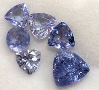 Close-up of six loose tanzanite gemstones showing color, cut, and inclusions.