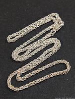 Silver twisted rope design chain necklace on black background, showing overall length and condition.