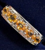 Close-up of silver ring with six oval citrine stones arranged in a row.
