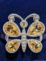 Close-up of silver butterfly ring showing pear-shaped yellow citrine stones on wings and small clear stones on butterfly body.