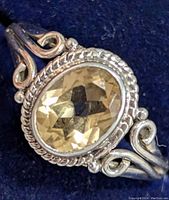 Close-up of the silver citrine ring showing the oval faceted citrine gemstone and detailed scrollwork on the band.