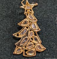 Close-up of the silver Christmas tree pendant taken from above, showing the intricate pattern of hollow teardrop shapes and diamond in the star.