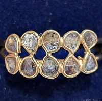 Close-up top view of silver ring showing multiple pear-shaped diamonds in gold bezels arranged side by side.