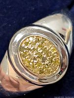 Close-up front view of the silver ring highlighting the oval diamond cluster in the center.