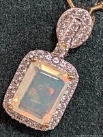 Close-up of rectangular silver opal and cubic zirconia pendant showing gemstone details and silver setting.