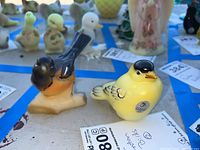 Two glass bird figurines grouped together on a surface with price tags visible.