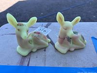 Front view of two Fenton deer figurines with hand-painted floral accents on a table.