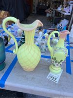 Both ewers side by side on table with other glassware
