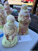 Pair of two signed Fenton Santa Claus figurines on outdoor table, showing overall scale and coloring.