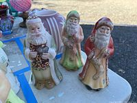 Three Santa figurines on table, showing full lot