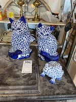 Photo showing two cat figurines and one frog figurine all decorated with blue and white scale-like pattern on ceramic material