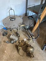 Overview of four hanging lamps and lanterns on floor, showing metal and glass components, dusty and worn condition
