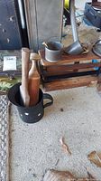 Overview of vintage kitchen items including wooden utensils, small metal pitcher, and tin box on a concrete floor.