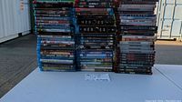 Wide view of multiple stacks of Blu-ray and HD DVD video discs with some visible titles.