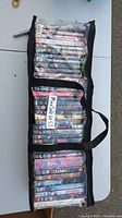 Black carrying bag with transparent pockets filled with DVDs showing titles stacked inside.