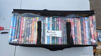 Photo showing the black carrying bag filled with 37 DVDs visible through transparent sides, DVDs arranged vertically.