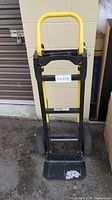 Front view of Harper dolly cart showing yellow handle, black frame, and base plate.