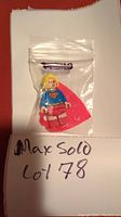 Front view of LEGO DC Supergirl minifigure inside a small plastic bag along with a red cape, placed on white paper with lot number written.